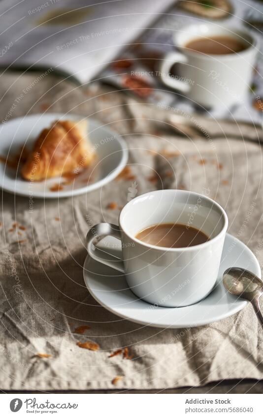 Gemütliche Frühstücksszene mit Kaffee und Croissants Tisch Tasse Leinen rustikal gemütlich Morgen Teller Löffel Gewebe Textur warm Licht Getränk melken weiß