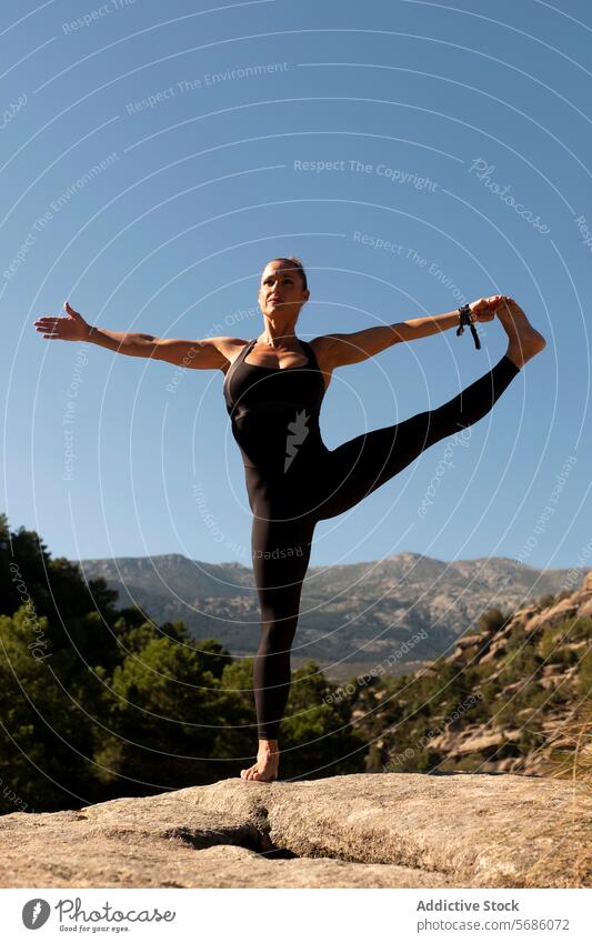 Schlanke Frau übt Standing Split Yoga-Pose auf felsigen Klippe in der Nähe von Bergen beweglich Dehnung Samsahate Hanumanasana Barfuß Leggings