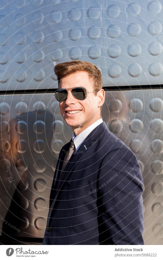 Stilvoller Geschäftsmann genießt das Sonnenlicht in Madrid Lächeln Sonnenbrille Anzug modern Wand texturiert stechend Kleid jung männlich professionell Mode
