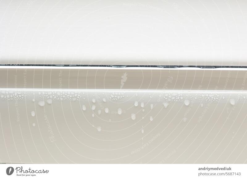 Kondensation von Wassertröpfchen auf weißem Metall-Kunststoff-Rahmen eines Fensters in einem Innenraum. Hohe Luftfeuchtigkeit. Feuchtigkeitskondensationsprobleme, heißer Wasserdampf kondensiert am Fenster in der kalten Jahreszeit.