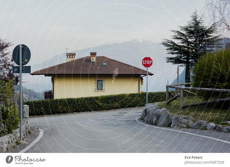 Gelbes Haus an einer Straße an einem Berghang mit Bergen im Hintergrund Blick Tenno Trentino Tourismus Urlaub Trento Berge u. Gebirge Italien Sommer Landschaft