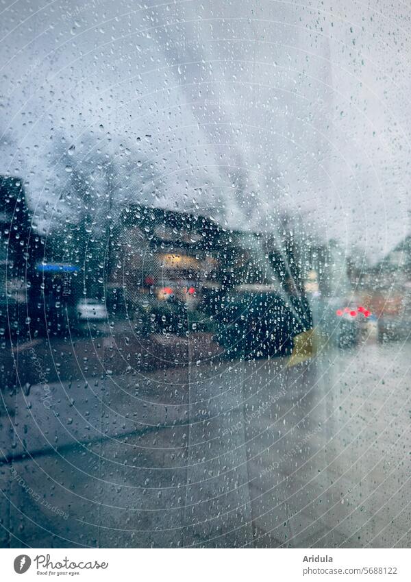 Einkaufsstraße spiegelt sich in Fensterscheibe mit Regentropfen Scheibe nass Wassertropfen schlechtes Wetter Regenwetter grau trüb Häuser Straße Gehweg