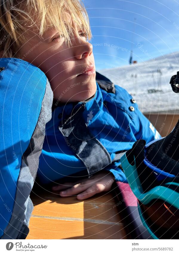 Pause im Skiurlaub Winter Schnee Junge träumerisch Außenaufnahme Farbfoto Natur portrait nachdenklich Sonne genießen Porträt Erholung blond schön Sonnenlicht