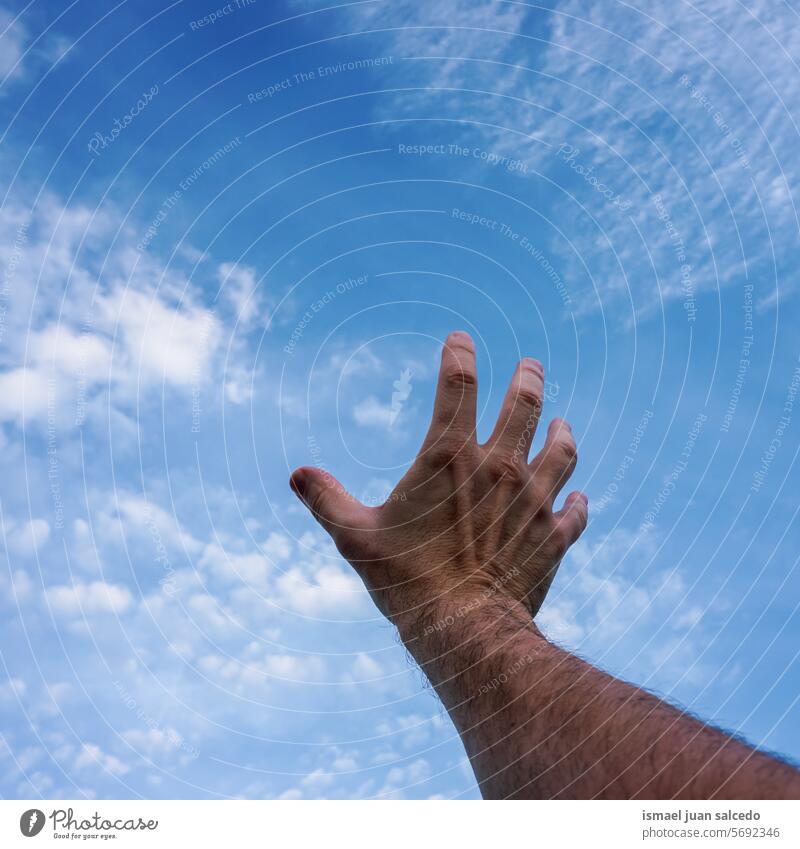 Hand, die gestikuliert und den blauen Himmel erreicht Arme Finger Haut Handfläche Körperteil hochreichen Hand erhoben Arm angehoben Blauer Himmel berührend