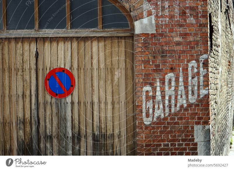 Alter verblichener weißer Schriftzug Garage in Versalien auf der alten rotbraunen Backsteinmauer einer Autowerkstatt mit Halteverbot in den Gassen der Altstadt von Brügge in Westflandern in Belgien