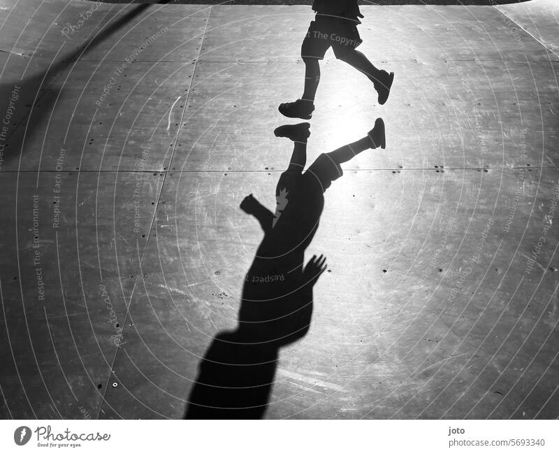 Silhouette von einem Kind rennt spielend auf einer Skaterbahn Silhouette Menschen Silhouettenfotografie Schatten Schattenspiel Schattenwurf Schattenbild Kinder