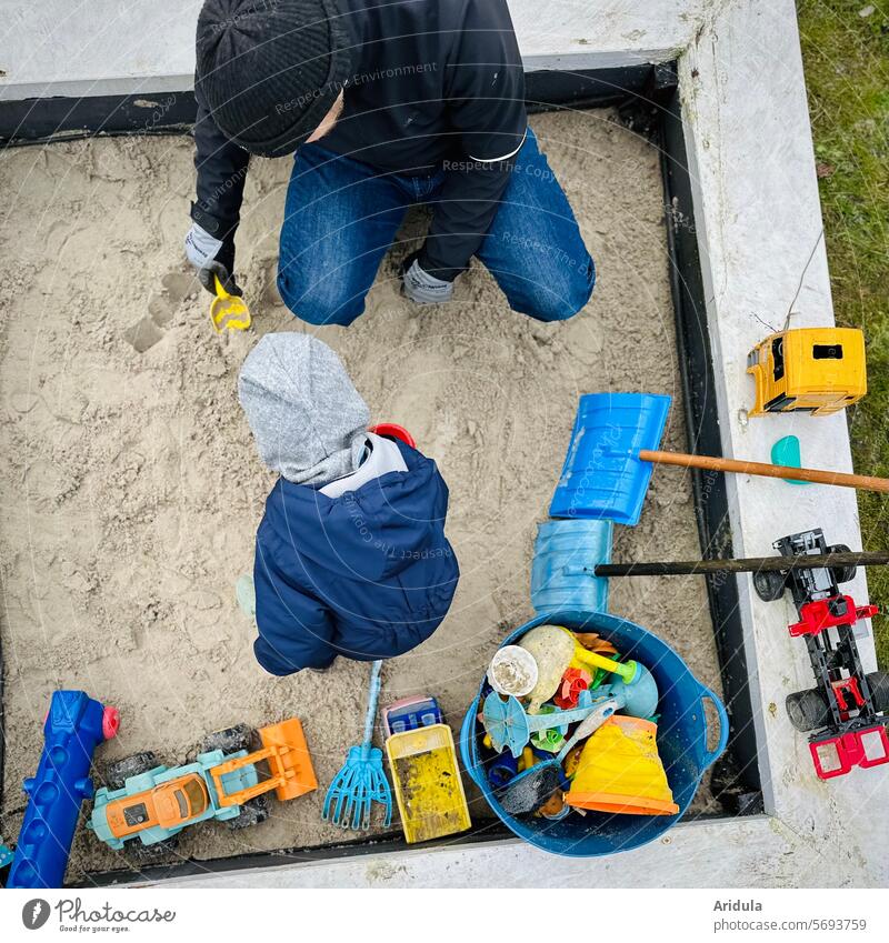Mann und Kind spielen in einer Sandkiste Spielzeug Vater Elternzeit Freizeit Kindheit Papa Glück Familie Menschen Garten Schaufel Harke Bagger Eimer