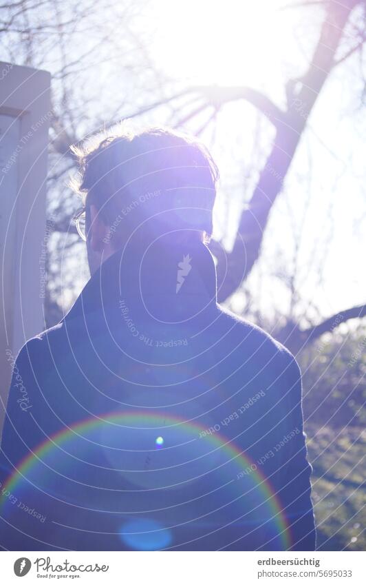 Mann studiert Infotafel und steht mit Rücken zur Kamera. Gegenlichtaufnahme mit Blendflecken Sonnenlicht Lichterscheinung lens flare blendenflecken Regenbogen