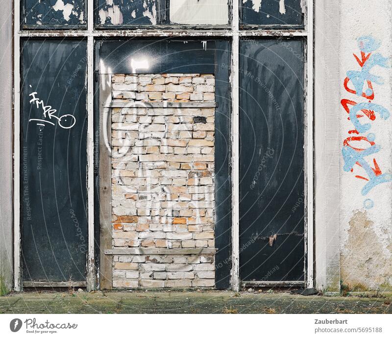 Hauswand, ehemals modernes Portal mit zugemauerter Tür, Graffiti Wand mauern zumauern geschlossen verschlossen Eingang Ausgang ausweglos Zugang Zerfall