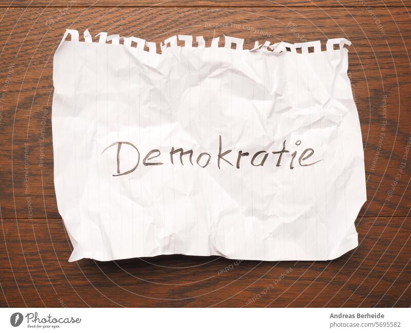 Zerknittertes Papierblatt mit dem Wort Demokratie auf einem Holztisch Frieden weltweit Einheit Zusammengehörigkeitsgefühl Abstimmung Konzepte Nachricht Idee