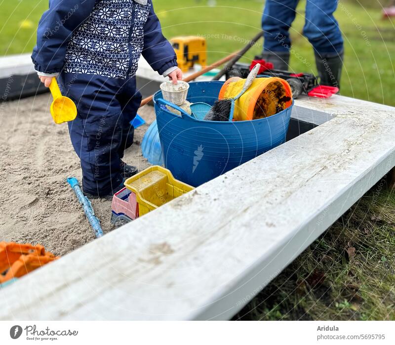 Kleinkind spielt in der Sandkiste Kind Kindheit Schaufel Bagger Kipplader Förmchen spielen Garten Rasen Sandkasten Kindergarten Spielzeug Spielplatz Freude