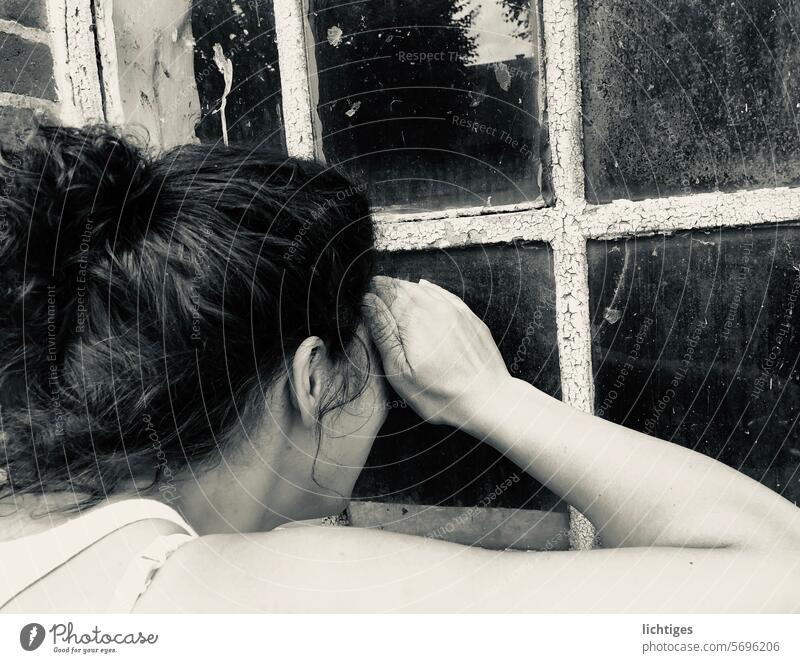 Junge Frau, die durch ein altes Fenster in eine Scheune kiebitzt neugierig Neugier hineinschauen einblick ausblick