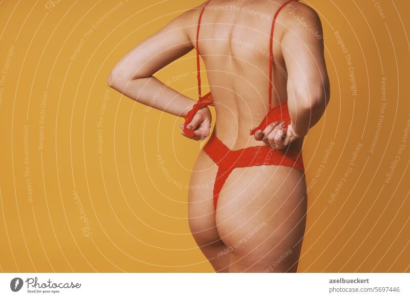 Frau in roter Unterwäsche entkleidet sich und zieht BH aus Ausziehen abfliegend Dessous sich[Akk] ausziehen Tanga Frauenunterhose Streifen aufgeilen Striptease