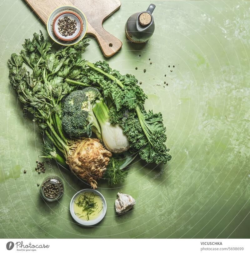 Grünes Gemüse auf Tisch Hintergrund mit Schneidebrett und Zutaten, Ansicht von oben grün Top Sellerie Fenchel Brokkoli Kale Overhead flache Verlegung roh
