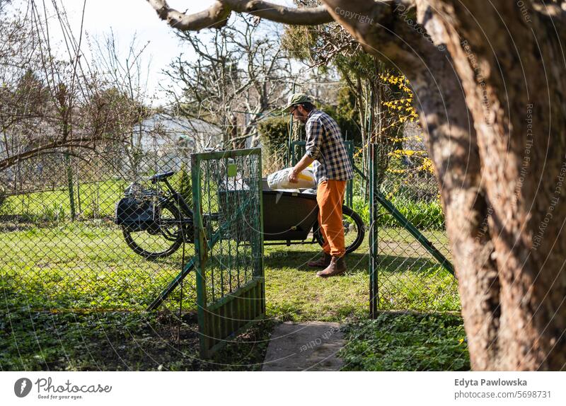Mann mit Lastenfahrrad bei der Arbeit in seinem Kleingarten Lastenrad Fahrrad Gartengeräte Freizeitaktivitäten Lebensstile Gartenarbeit Aktivität Tag im Freien
