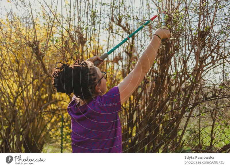 Frau beim Beschneiden von Sträuchern in ihrem Kleingarten im Frühling Beschneidung Buchse Gartengeräte Freizeitaktivitäten Lebensstile Gartenarbeit Hinterhof