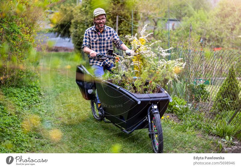 Mann mit Lastenfahrrad bei der Arbeit in seinem Kleingarten Lastenrad Fahrrad Gartengeräte Freizeitaktivitäten Lebensstile Gartenarbeit Aktivität Tag im Freien