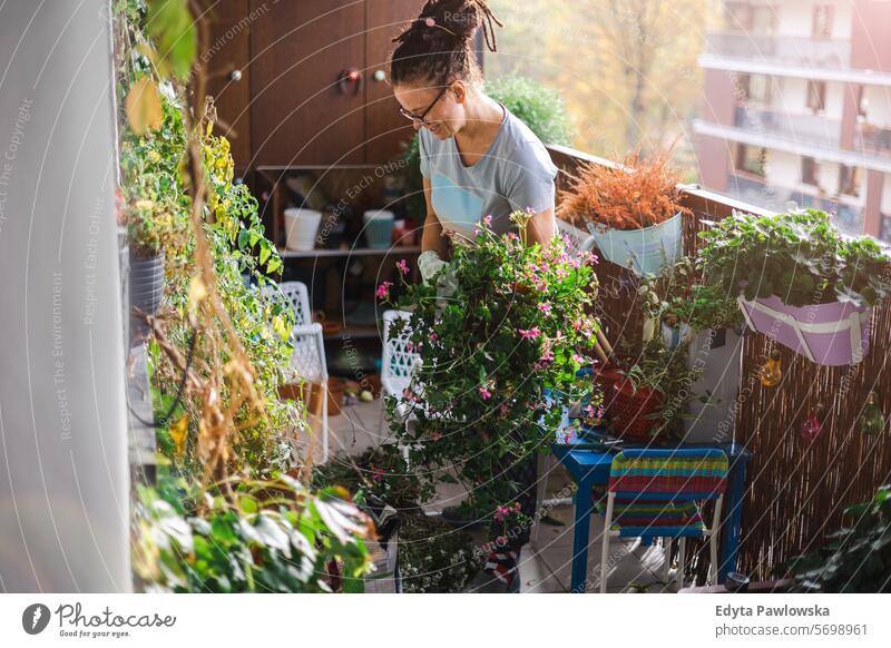 Frau, die sich um ihre Pflanzen auf dem Balkon kümmert Überstrahlung frisch geblümt Flora Blüte Hobby Blumenhändler Topf natürlich Person Erwachsener Botanik