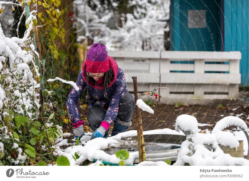 Frau bei der Arbeit in ihrem Kleingarten im Winter Schnee kalt Wetter Gartengeräte Freizeitaktivitäten Lebensstile Gartenarbeit Hinterhof Aktivität Tag