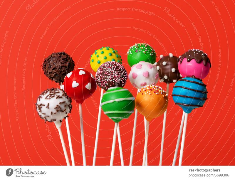 Bunte Cake Pops isoliert auf einem roten Hintergrund Sortiment backen Ball blau hell Kuchen Kuchenpops Bonbon Schokolade abschließen farbenfroh Farben