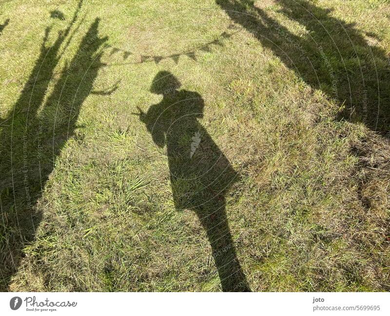 Schatten einer Frau im Gras mit Wimpelkette bei einer Gartenparty friedenszeichen Peace Peace Zeichen Schattenspiel Silhouette Partygast Partystimmung