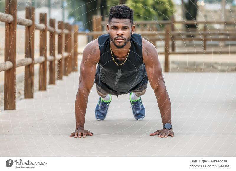 Starker Sportler im Stadtpark auf dem Brett Athlet Aufwärmen Schiffsplanken hochschieben Bauchmuskeln Kraft Kerngehäuse Übung Muskel Mann männlich jung