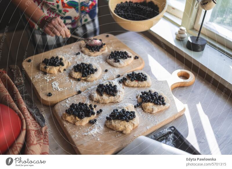 Frau bereitet zu Hause Heidelbeerbrötchen zu (Jagodzianka - traditionelles polnisches süßes Brötchen mit Heidelbeerfüllung) Blaubeeren Mehl Beerenfrucht Frucht