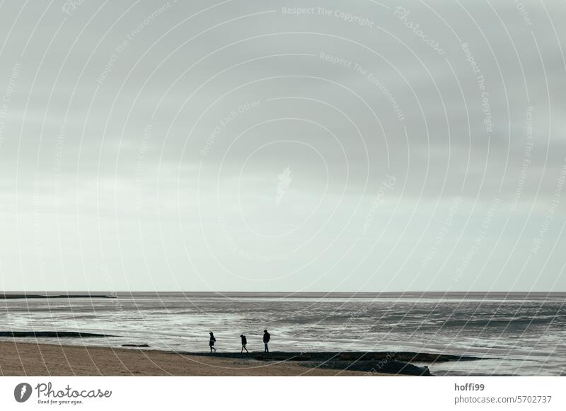 drei Menschen bei bedecktem Wetter am Strand der Nordsee weite Einsamkeit grau silber Nebelstimmung minimalistisch maritim schlechtes Wetter kalt Minimalismus