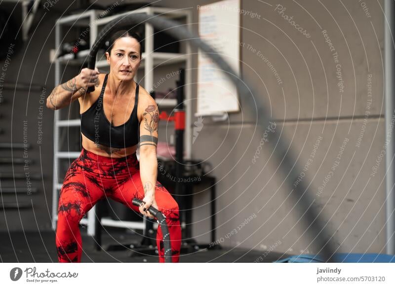 Weibliche Athletin beim Training in einem Fitnessstudio mit Sportgeräten Kampfseil Frauen Gerät Übung Gesundheit Wellness Routine aktiv Körper Konditionierung