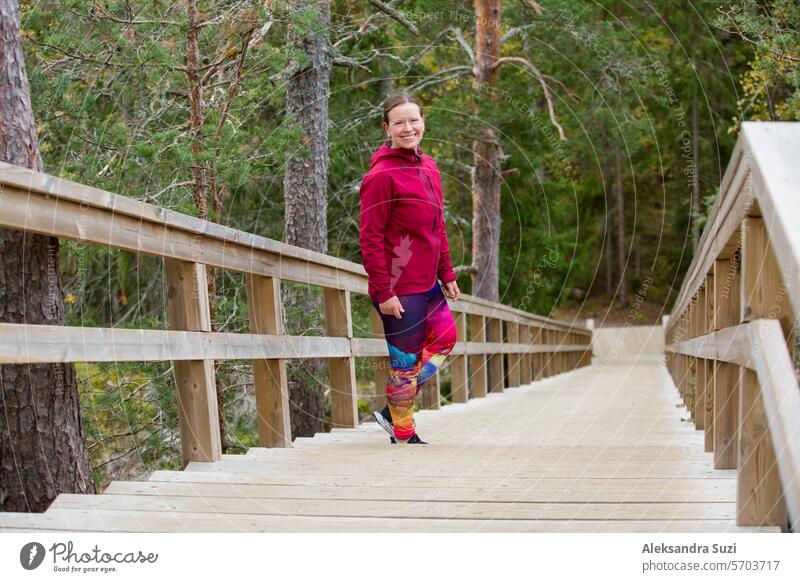 Sportliche Frau mittleren Alters läuft die Fitnesstreppe in einem Naturpark im Wald hinauf aktiv Aktivität allein Athlet sportlich Herz Kaukasier