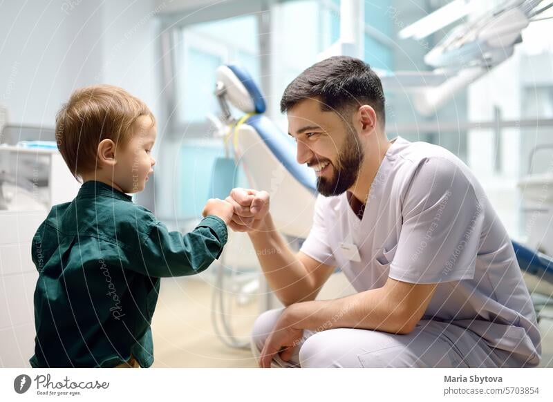 Freundlicher Zahnarzt begrüßt süßes Kleinkind im Büro. Arzt ermutigend mit kleinen Kind Patient und geben ihm "high five". Kinderarzt nimmt Kontakt mit kleinem Patienten auf
