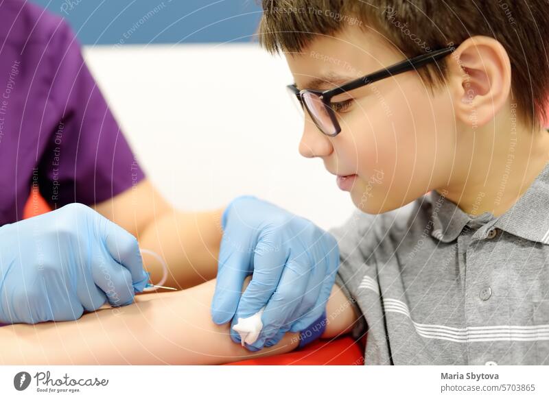 Eine Krankenschwester nimmt einem Kind Blut ab. Nahaufnahme der Hand eines Jungen bei der Entnahme einer Blutprobe zur Untersuchung in einem modernen Labor oder Krankenhaus.