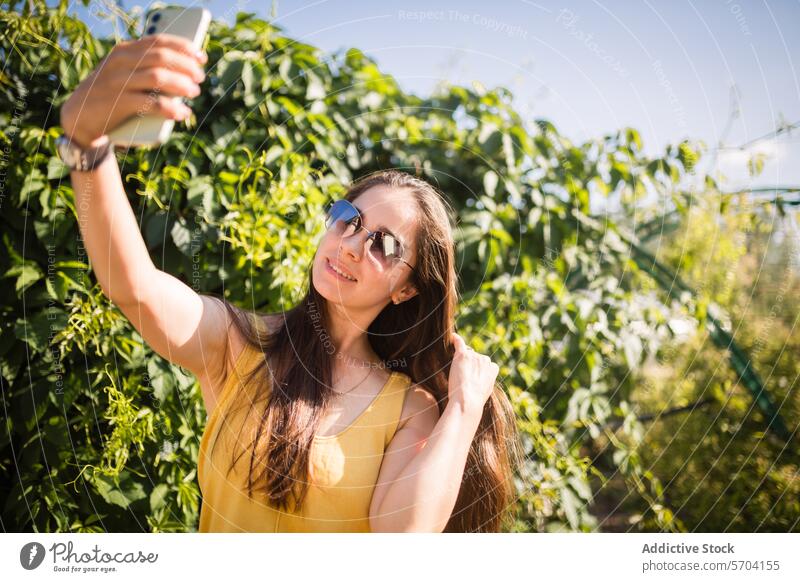 Junge Frau genießt den Sommer und macht ein Selfie im Freien Smartphone Garten sonnig Freude erfassend Moment heiter jung fotografierend Freizeit lässig