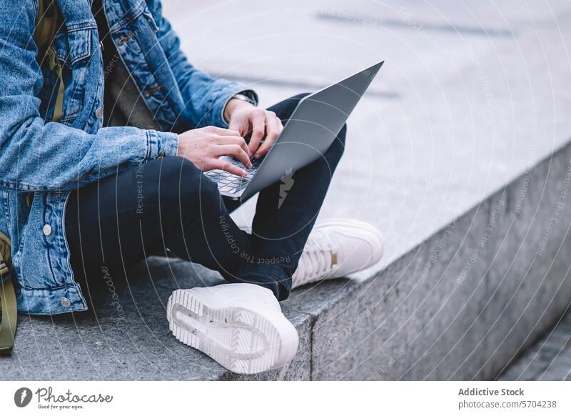Junger Mann arbeitet an seinem Laptop, während er auf den Stufen eines belebten Madrider Platzes sitzt jung arbeiten Quadrat Freitreppe im Freien Stadtleben