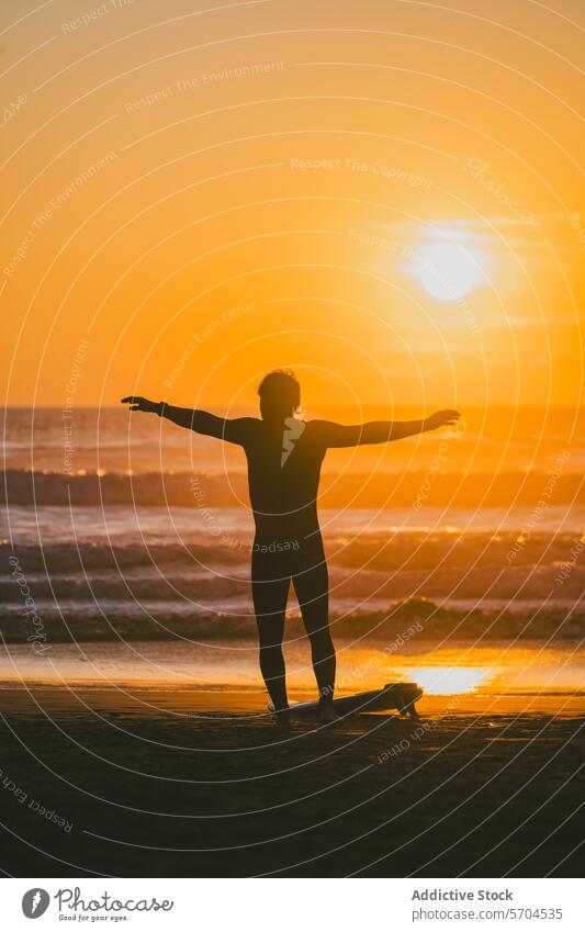 Männlicher Surfer mit ausgebreiteten Armen steht am Strand mit Surfbrett bei Sonnenuntergang Mann MEER Silhouette Wasser winken Natur Sand Ufer Meer Küste