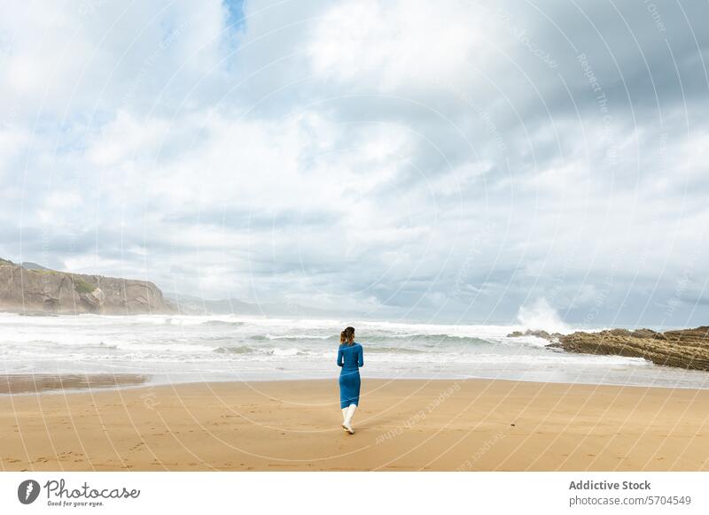 Frau, die am Sandstrand in der Nähe des wogenden Ozeans spazieren geht Strand MEER Reisender bewundern winken Meer Küste Spaziergang Ufer Tourist bedeckt