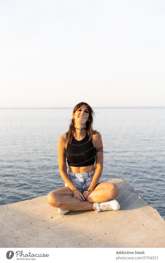 Junge Frau sitzt am Pier in der Nähe von Meerwasser Lächeln MEER Wasser Ausflug frisch Glück genießen Tourist sitzen Vergnügen positiv natürlich Rippeln froh