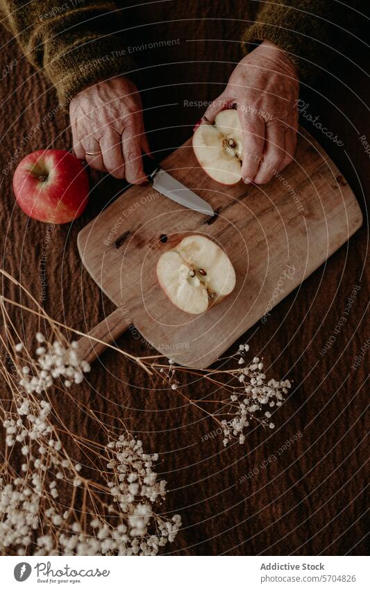 Ältere Hände schneiden einen Apfel auf einem Holzbrett älter Schneiden hölzern Holzplatte rustikal gemütlich gealtert Nahaufnahme frisch Gelassenheit
