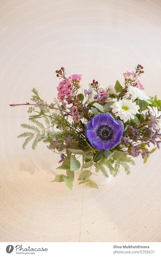 schönen Blumenstrauß mit lila Anemone und rosa Wachs Blume auf weiß beige neutralen Hintergrund kopieren Raum oben und unten. Blumenarrangement vertikale Kulisse.