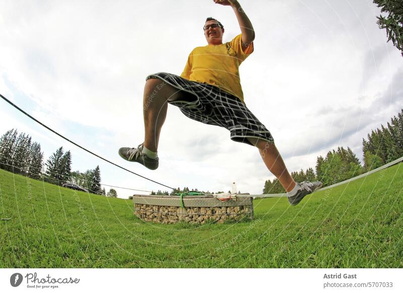 Ein junger Mann hat Spaß auf einer Slackline erlahmen Sickerwasser balancieren Gleichgewicht Sport freizeit Freizeitsport aktiv Aktivität Bewegung bewegen Spass