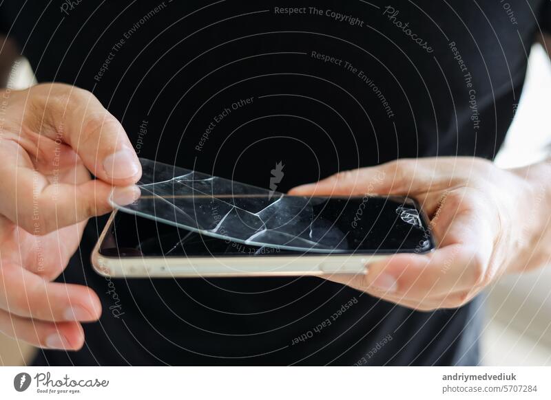 Prozess unerkennbar Techniker entfernt gebrochen und alt gehärtetem Glas Bildschirmschutz von Smartphone, Nahaufnahme. Dienstleistungen zum Kleben und Ersetzen von beschädigtem Schutzglas.