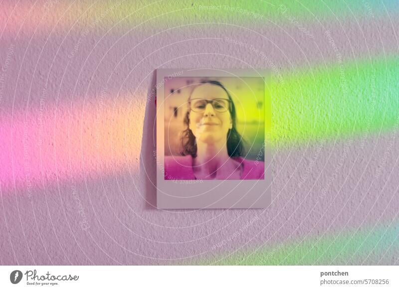 polaroid einer frau hängt an einer wand und ist beflutet von regenbogenfarbigem licht selfie brille verziert hängen Frau mehrfarbig Erwachsene spektralfarben