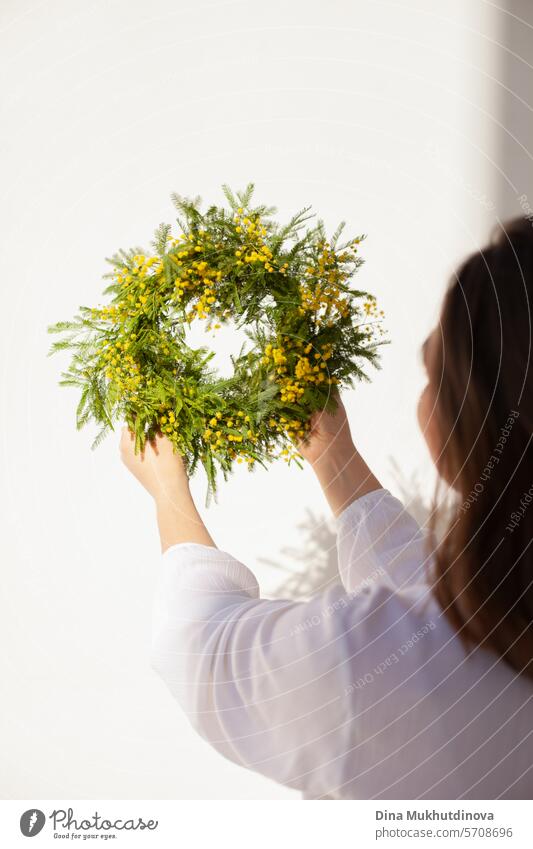 weibliche Floristin hält schönen Kranz mit gelben Mimosen Frühlingsblumen. Frische elegante Wohnkultur. Florist Arbeit. Totenkranz Blumen Salon Vase Dekor
