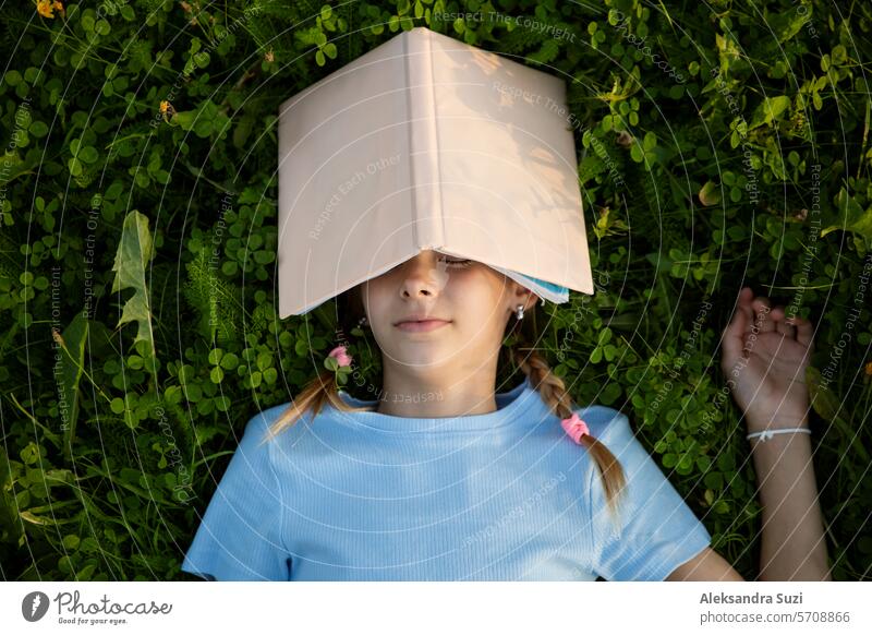Eine junge Studentin schläft mit einem Buch auf dem grünen Rasen im Park, studiert, schreibt, liest. attraktiv schön lässig Kind niedlich Bildung Genuss Frau