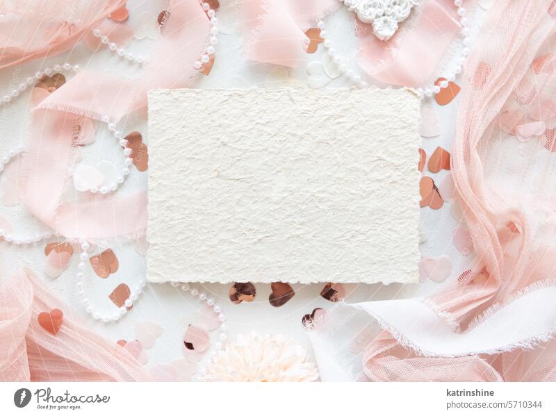 Karte in der Nähe von rosa Dekorationen, Herzen und Seidenbändern auf weißem Tisch Draufsicht, Mockup Hochzeit Attrappe Postkarte romantisch Valentinsgruß