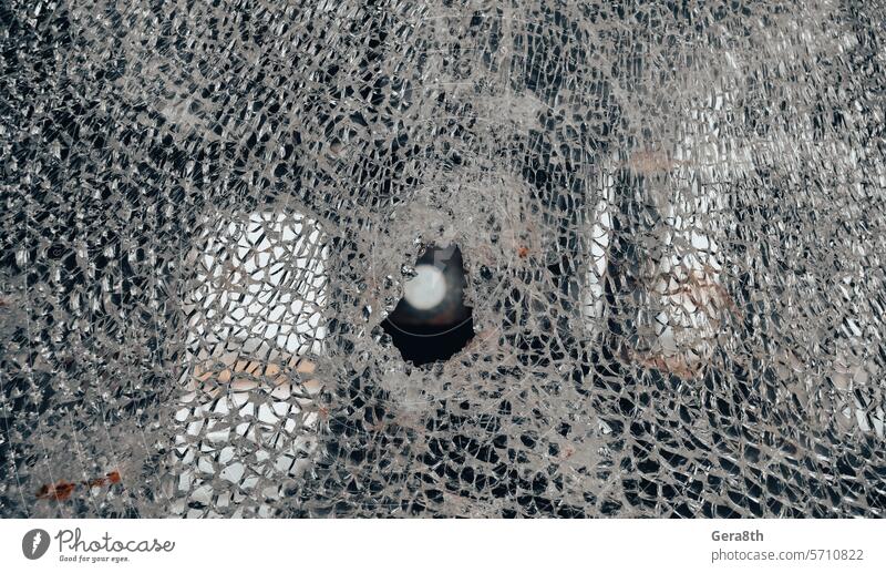 Einschussloch im Fensterglas mit Rissen abstrakten Hintergrund schließen Unfall gebrochen zerbrochenes Glas kaputtes Fenster Gewehrkugel Einschusstreffer