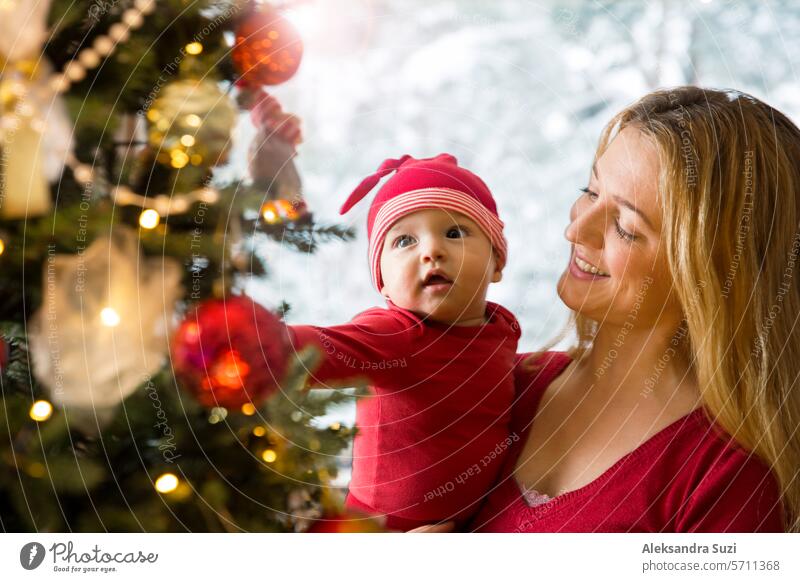 Kleines süßes Baby und seine Mutter genießen glänzende Lichter und Ornamente auf dem Weihnachtsbaum bezaubernd schön Pflege Feier heiter Kind Kinderbetreuung
