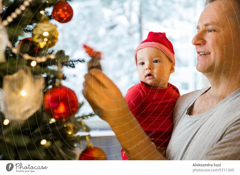 Kleines süßes Baby und sein Vater genießen die glänzenden Lichter und Ornamente am Weihnachtsbaum schön Junge Kaukasier Feier heiter Kind Kindheit Weihnachten