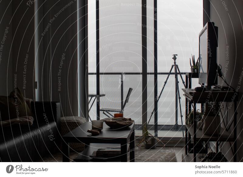 Gedämpftes Wohnzimmer mit Möbeln, die auf einen nebligen Balkon mit Stativ blicken Raum Wohnräume Wohnraum heimwärts Innenbereich Wohnung Innenaufnahme Farbfoto