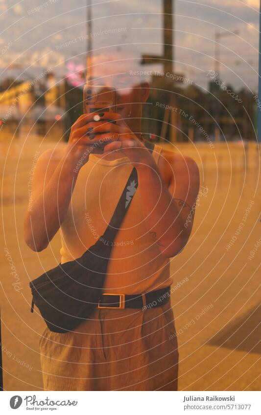 junger Mann macht ein Foto mit seinem Handy Sommer lässig Streetstyle trendy Tag Farbfoto modern Straße natürlich 1 Porträt urban Scheibe orange Model Stadt